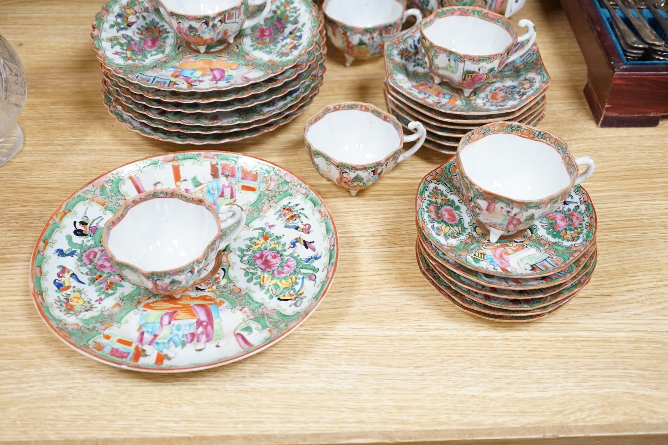 A Chinese famille rose six place setting tea service, including a large tea pot and cover, a smaller water pot and cover, two sugar bowls with covers, a large milk jug (handle broken) a small cream jug and a cake plate,(